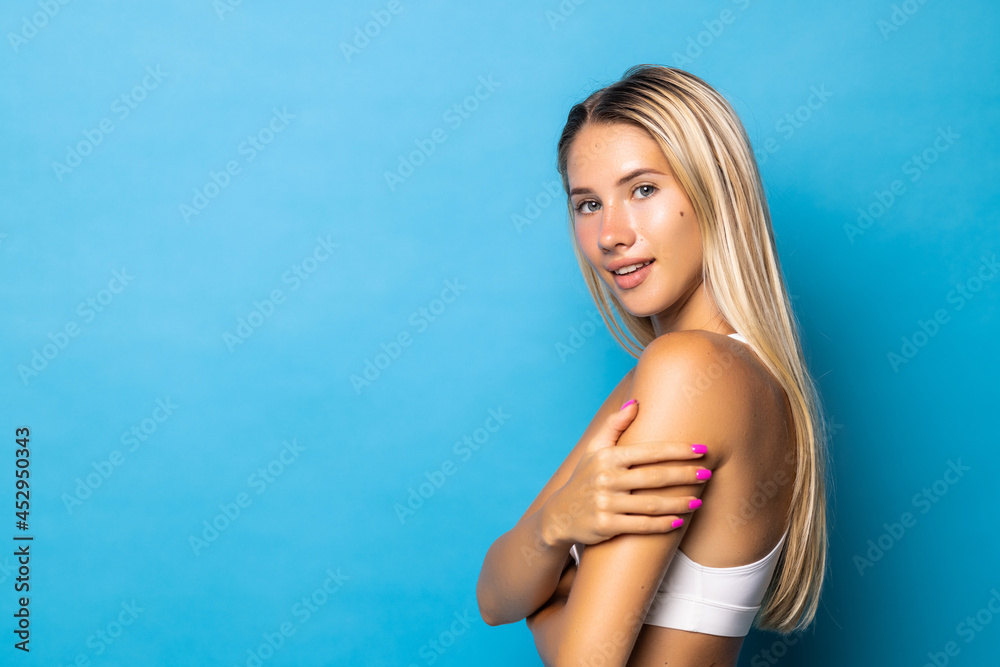 Sporty young girl posing in white underwear with perfect body on blue background.