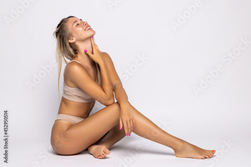Young woman sitting on the floor in underwear on beige background