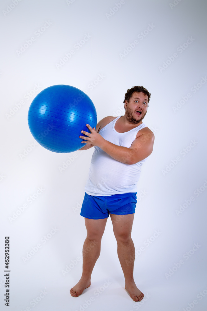 Funny fat man training with a fitness ball. Adult guy on a white background. Copy space. Active sports with a diet. Funny fat man training with a fitness ball. Adult guy on a white background. Copy space. Active sports with a diet.