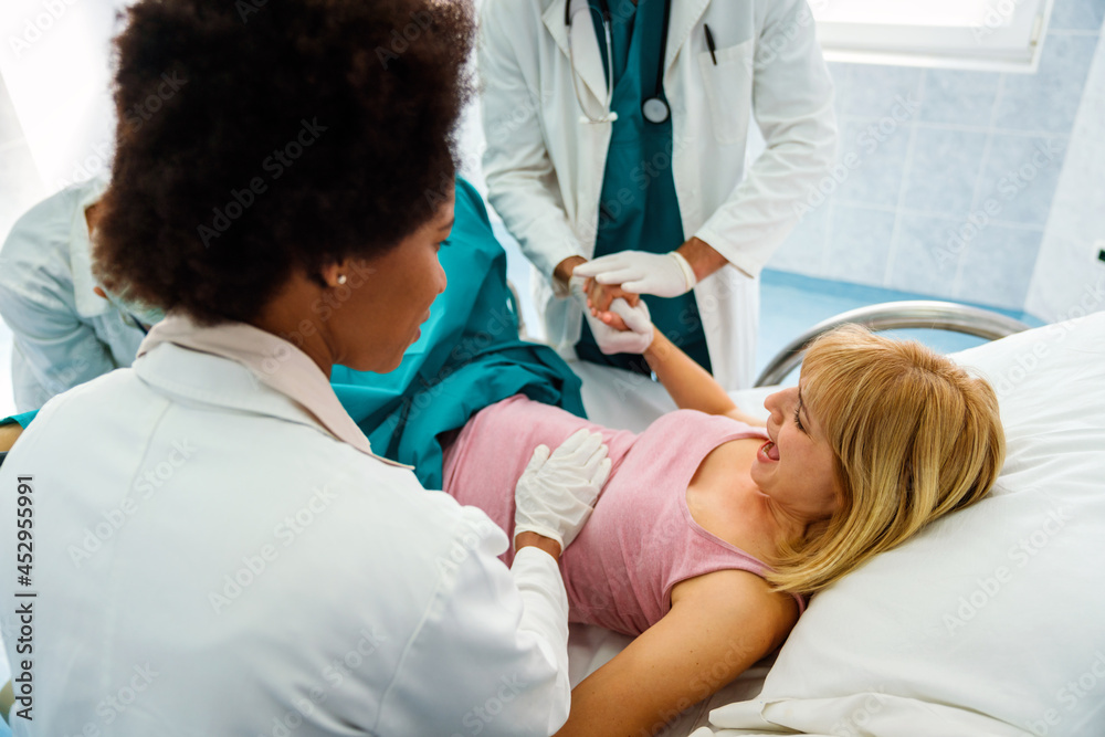 Obraz premium Pregnant woman pushes to give birth in hospital, obstetrician doctor assisting
