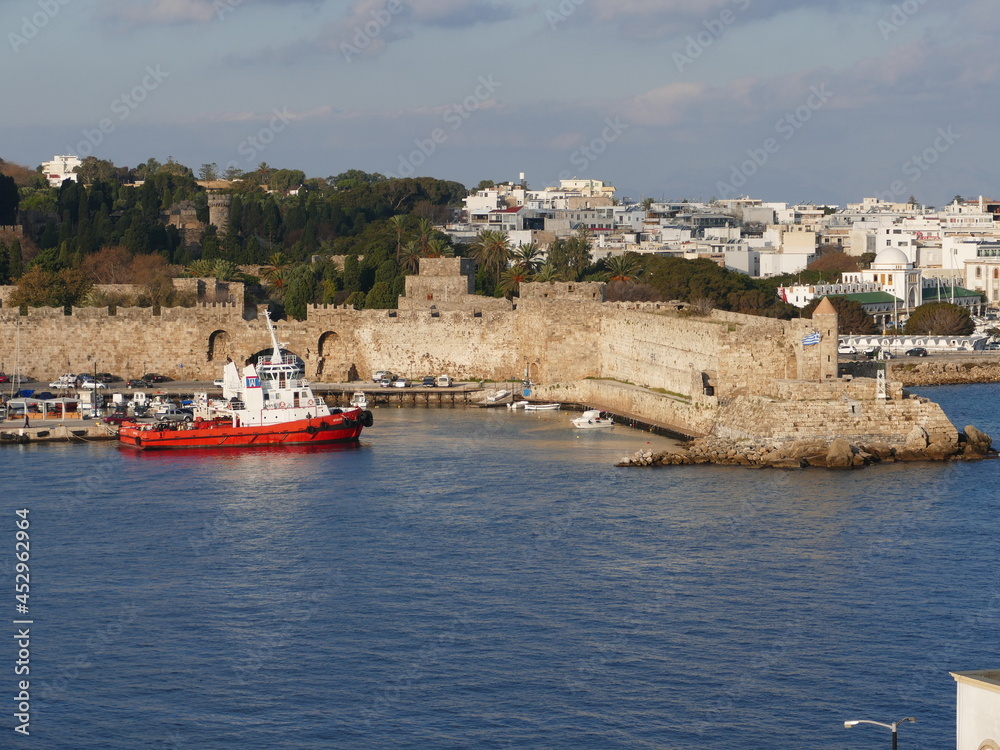 Tugboat in the Embaria port of Rhodes Town, Rhodes, Greece, on the headland of the Nailac Tower, on the right in the picture the Nea Agora market hall