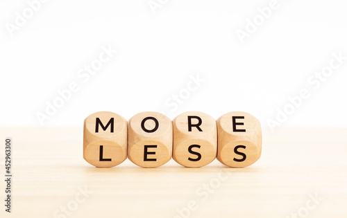 More and less word on changing wooden blocks. Copy space. White background photo