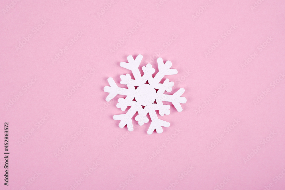 A white wooden snowflake isolated on a pink background.Multifunctional creative concept of minimalism of a Christmas card, eco-friendly natural Christmas tree toys.Happy New Year.Copyspace.