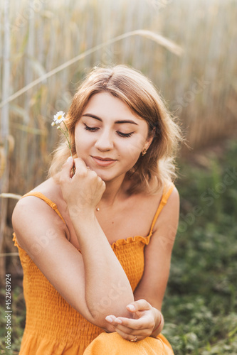 A young beautiful girl holds a chamomile flower