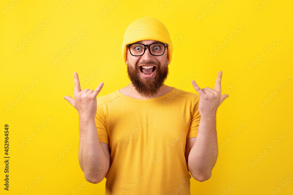 funny man makes rock n roll gesture over yellow background funny man makes rock n roll gesture over yellow background