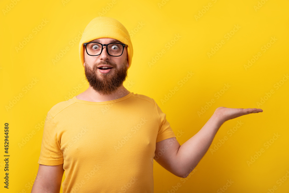 handsome caucasian man showing empty open hand over yellow background