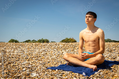 Teenage boy on a beach meditating