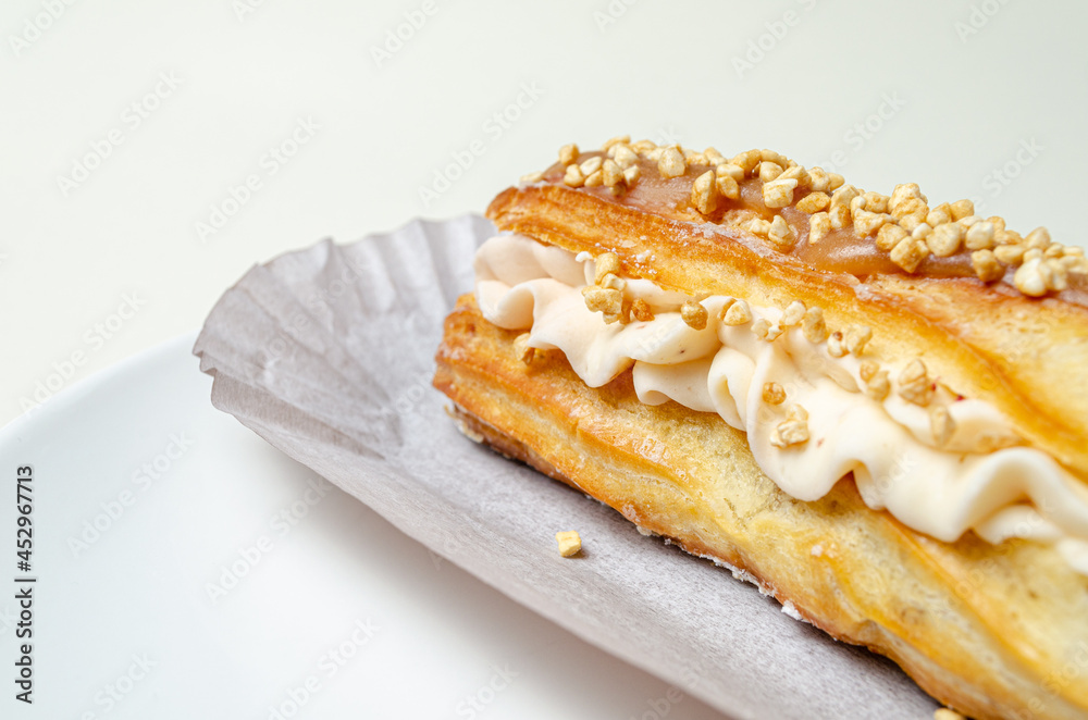 Eclair with cream and strawberries. On a white plate High quality photo Eclair with cream and strawberries. On a white plate High quality photo