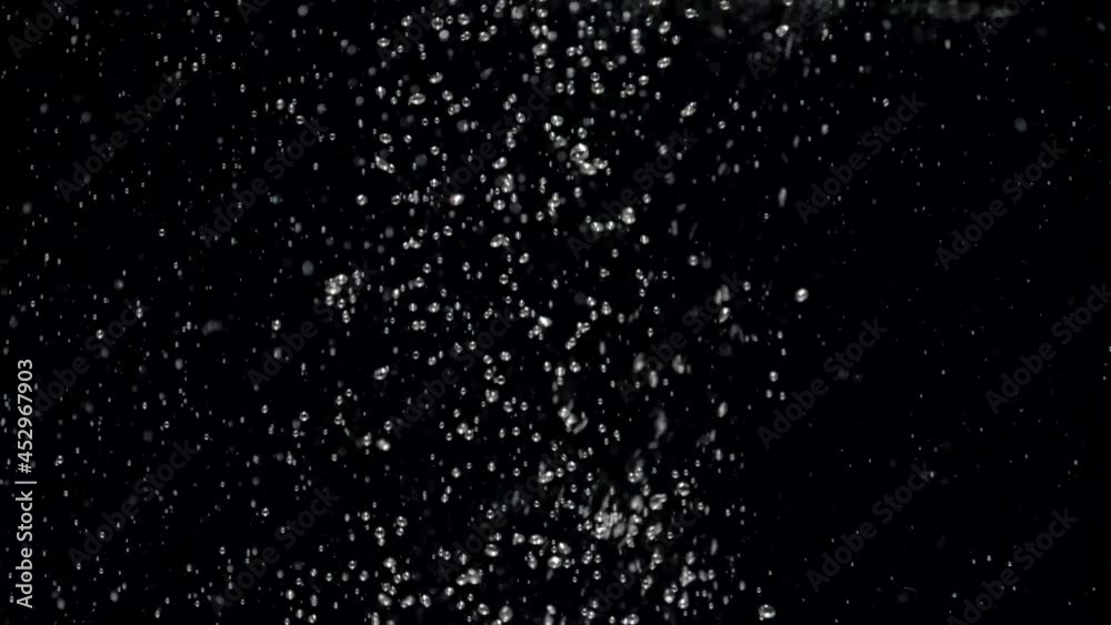 Slow motion stream of water drops down in aquarium on a black background. Slowmotion crystal clear water flow hits the surface and creates air bubbles Slow motion stream of water drops down in aquarium on a black background. Slowmotion crystal clear water flow hits the surface and creates air bubbles