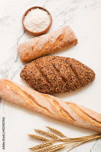 Bread, pastries on a light background. Bread with sesame seeds and seeds, bread texture. Delicious flavored bun. Lots of airy fresh bread.