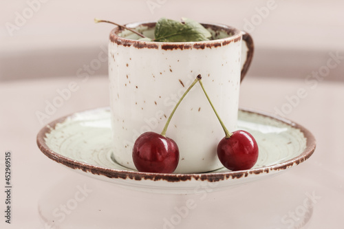 Wallpaper Mural A cup on a green saucer  and wwo red cherries. Still life with cherries Torontodigital.ca