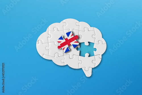 English learning concept, white jigsaw puzzle pieces with british flag a human brain shape on blue background photo