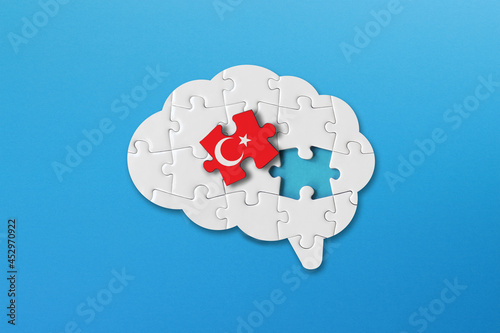 Turkish learning concept, white jigsaw puzzle pieces with turkish flag a human brain shape on blue background photo