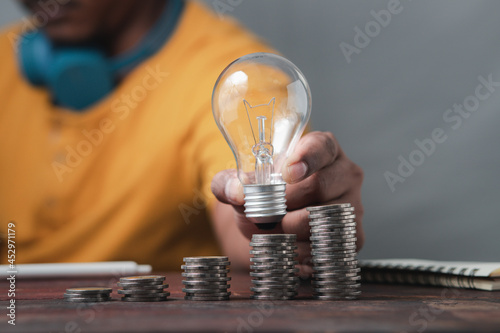 money saving concept Male businessman holding a light bulb showing new ideas, capital gains, financial gains.