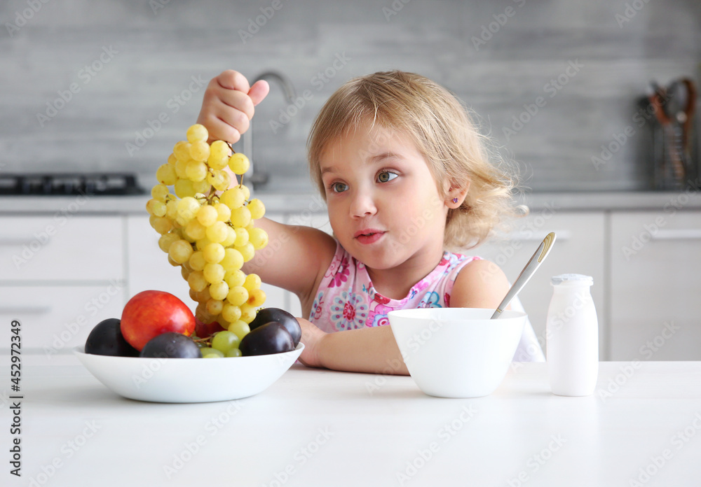 Child girl eating fruits. Little girl have a healthy meal at kitchen
