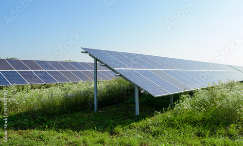 Solar panels installation above green grass under clear blue sky on a bright sunny day