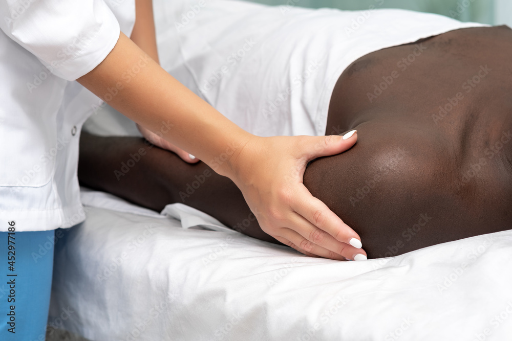 woman masseur doing massage of shoulder area of hand to black man