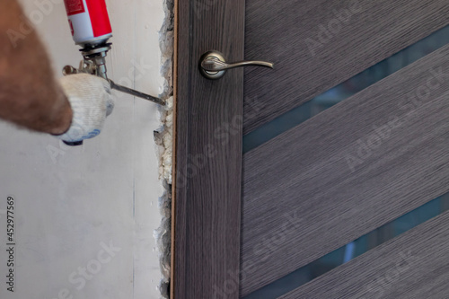 Installation of the door block. The worker fixes the door frame with foam.