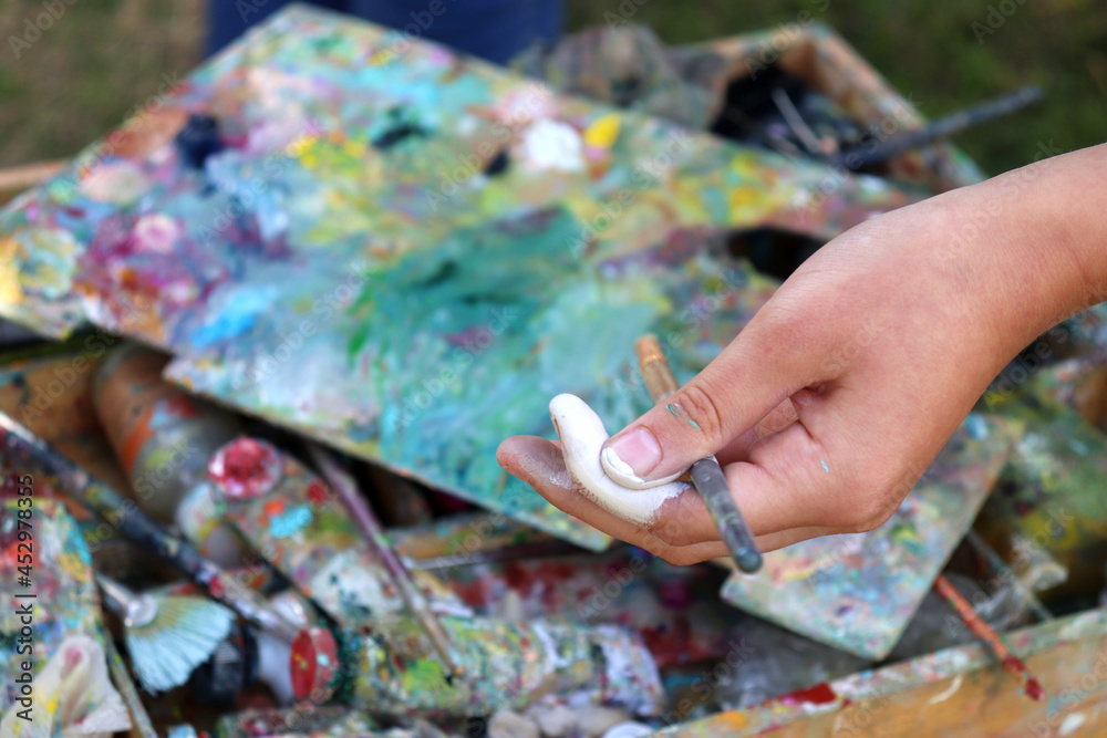 Female artist with palette and brushes in hand. Close-up