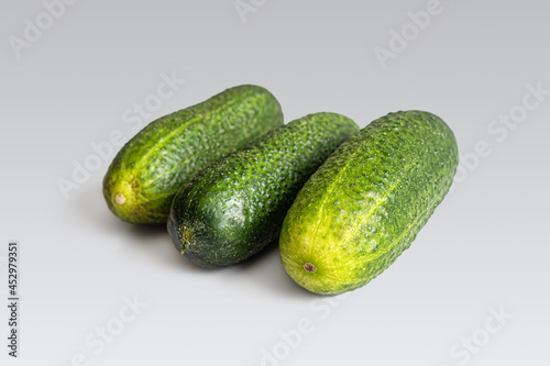 Three ripe cucumbers for salad on a light background