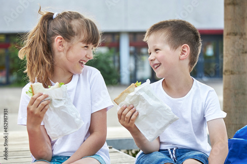 Snack during lessons. Close-up portrait of Happy children eating breakfast in the schoolyard. Meals for students during lessons photo