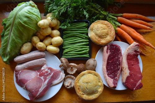 British food selection for steak dinner with loved one. Hand cut sirloin steaks from native Ruby Red Devon cattle country style pork sausages bacon topped and tailed green beans and shiitake mushrooms photo