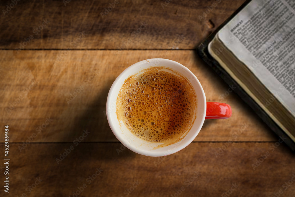 Fototapeta premium A picture of a coffee mug taken under controlled professional lighting on a wooden table beside a book.
