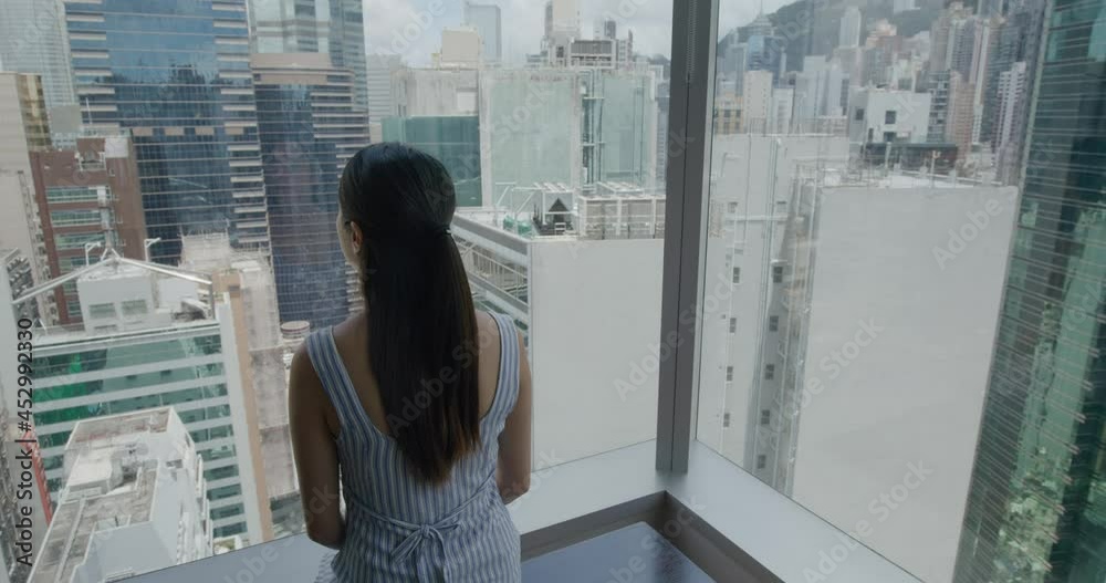 Woman look at the city view in Hong Kong at home Woman look at the city view in Hong Kong at home