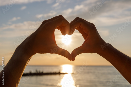 heart of love hands on the beach at sunset