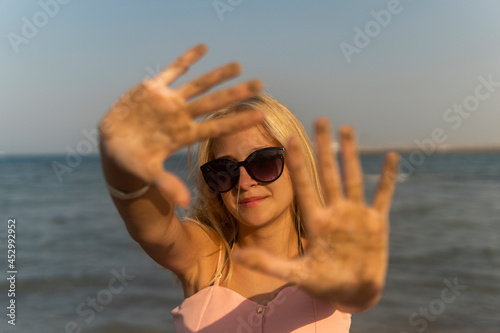 teenage girl blonde with glasses to keep her hands in the sand by the sea © Olleg1