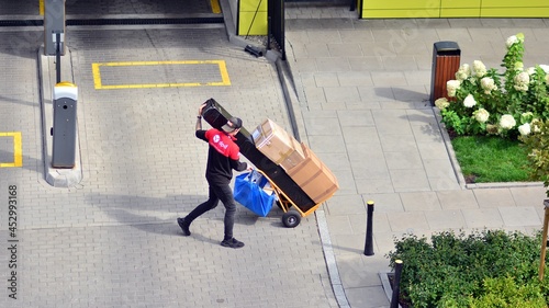 Wallpaper Mural Delivery man pushes hand truck trolley full of cardboards. Torontodigital.ca