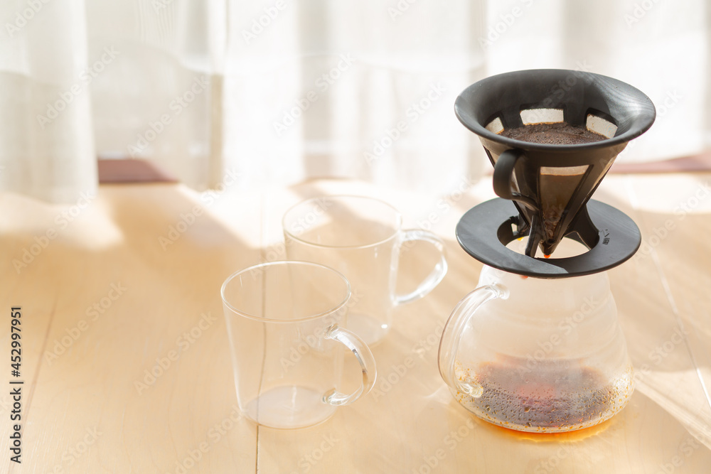 dripping coffee and two small glasses beside the window curtain and morning sunlight shedding into the room in tokyo, japan dripping coffee and two small glasses beside the window curtain and morning sunlight shedding into the room in tokyo, japan