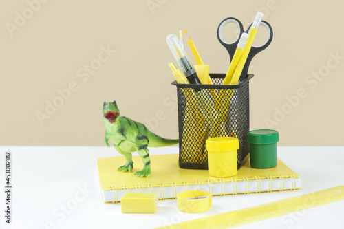 Education and back to school concept  notebooks with school stationery and green dinosaur toy on the table. 