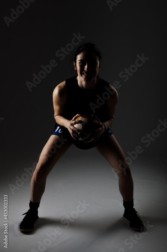 Handball player posing on dark gray background. Girl posing with ball.