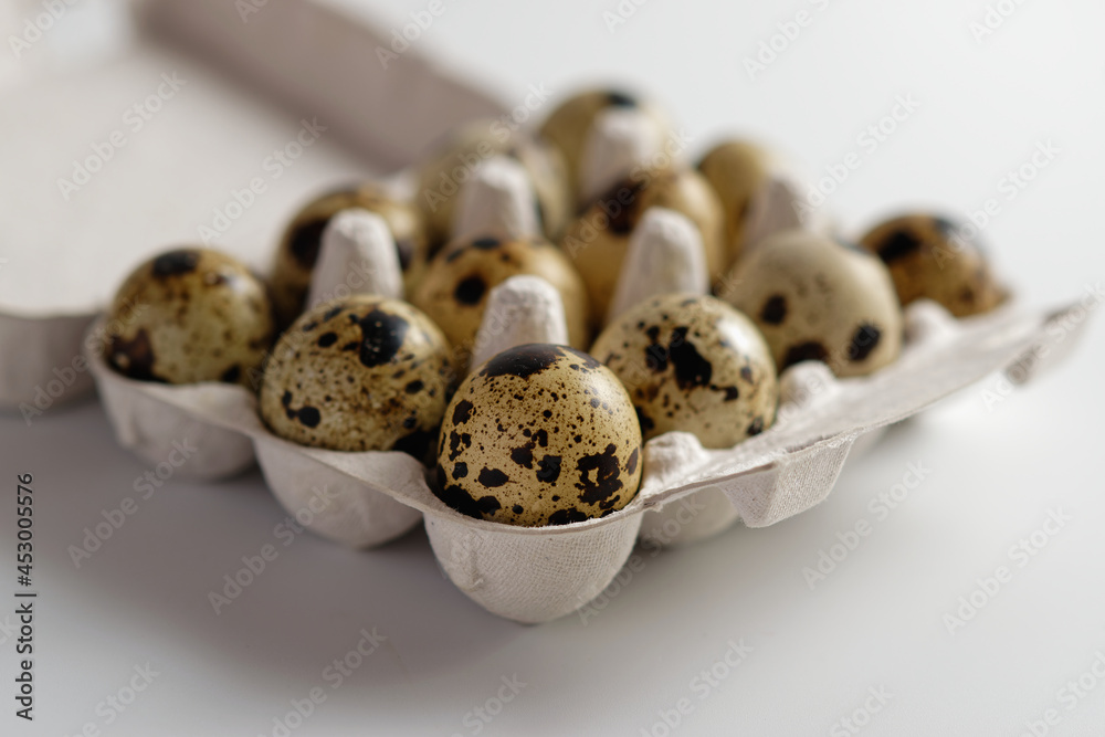 Close up of several quail eggs in a white egg carton. Isolated on white background. Close up of several quail eggs in a white egg carton. Isolated on white background.