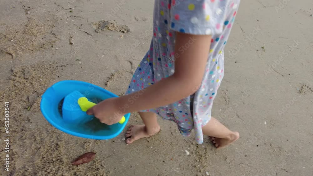 Slowly follow little girl use blue boat toy carry sea water at beach Slowly follow little girl use blue boat toy carry sea water at beach