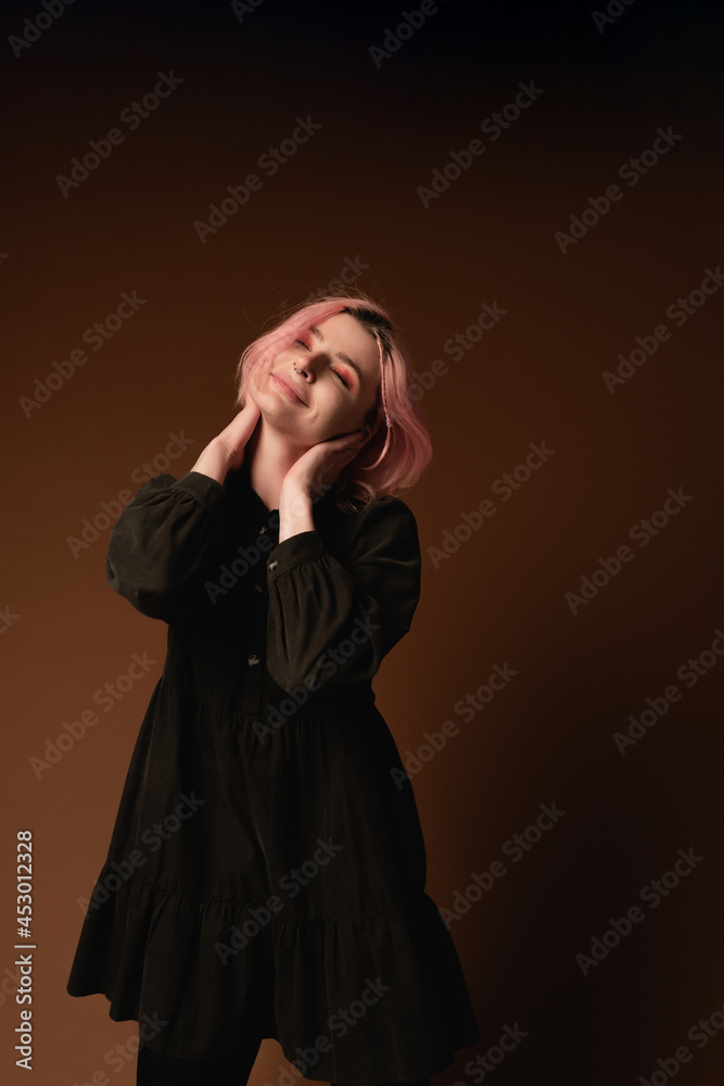 Young woman girl with pink hair at brown wall background studio portrait. People sincere emotions lifestyle concept 