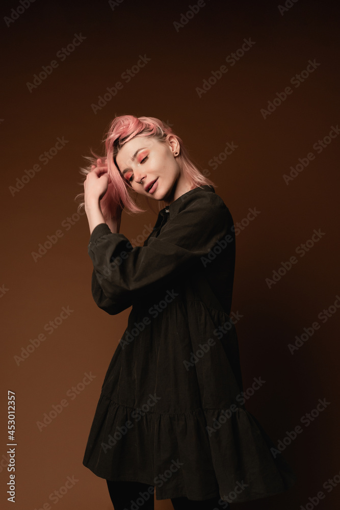Young woman girl with pink hair at brown wall background studio portrait. People sincere emotions lifestyle concept 
