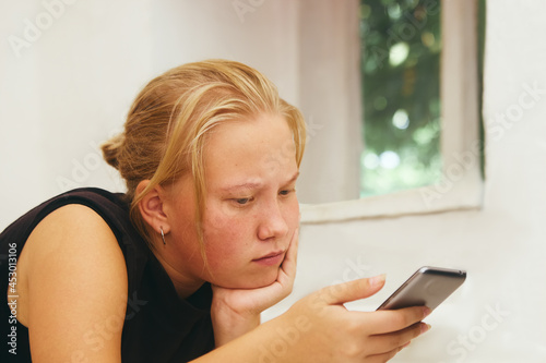 Teen girl holds a mobile phone in her hand and looks at the screen