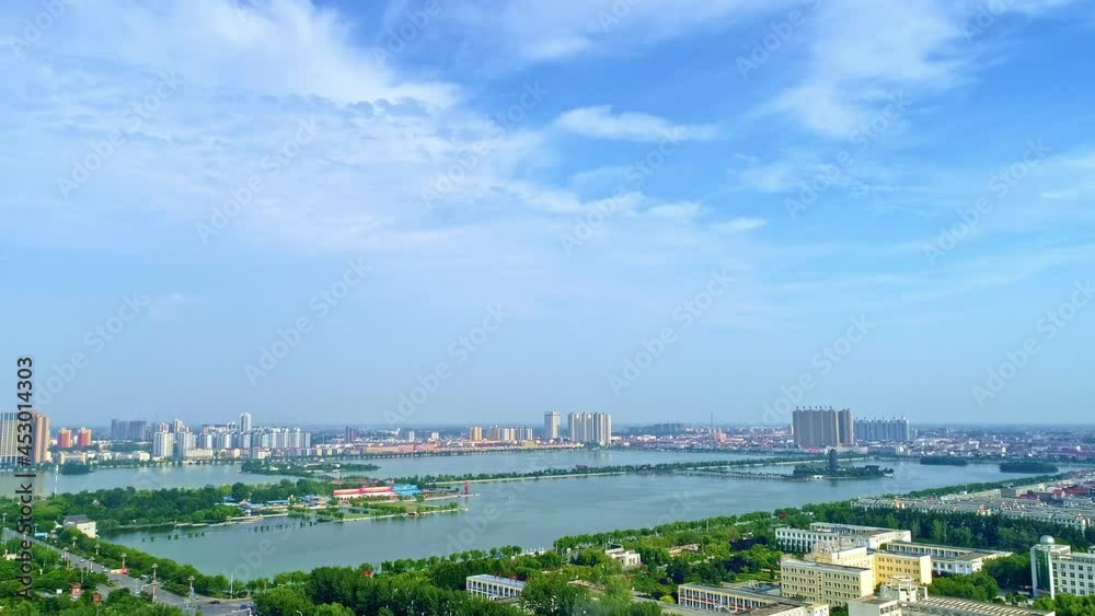 Aerial shot. Under blue sky and white clouds, a beautiful man-made lake in the center of a Chinese city, a good place for urban residents to relax. Panning forward Aerial shot. Under blue sky and white clouds, a beautiful man-made lake in the center of a Chinese city, a good place for urban residents to relax. Panning forward
