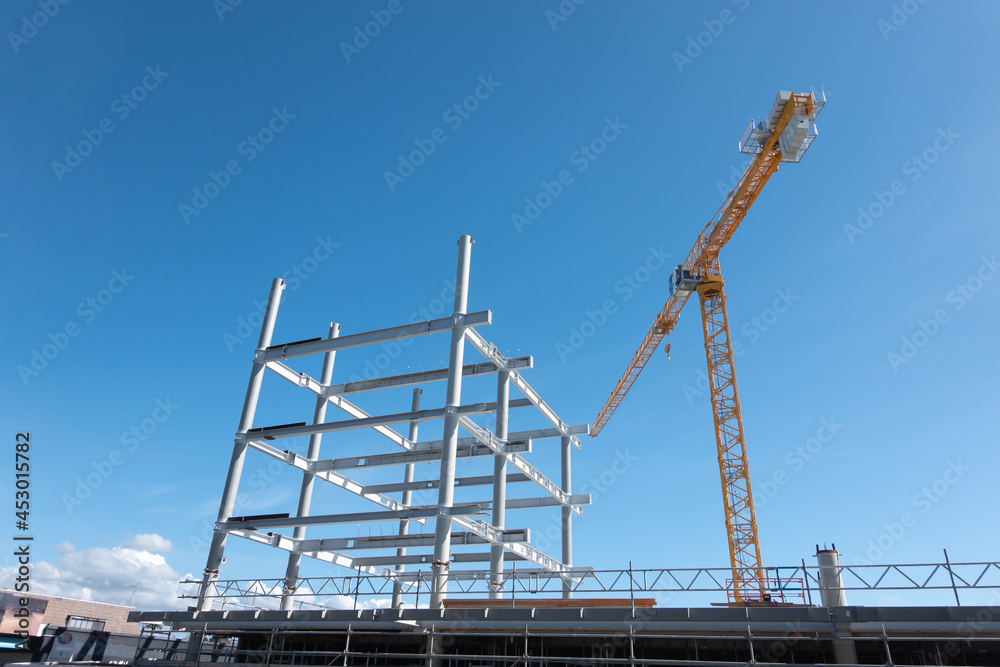heavy steel frame rising into blue sky as new building being constructed