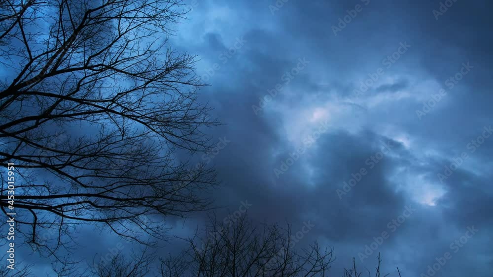 Time-lapse shot of withered branches in the foreground and billow dark clouds Time-lapse shot of withered branches in the foreground and billow dark clouds