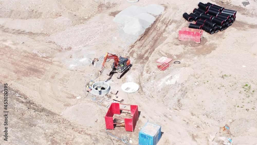 Excavation digger vehicle preparing concrete pipe conduit aerial view on housing development construction site left push in Excavation digger vehicle preparing concrete pipe conduit aerial view on housing development construction site left push in