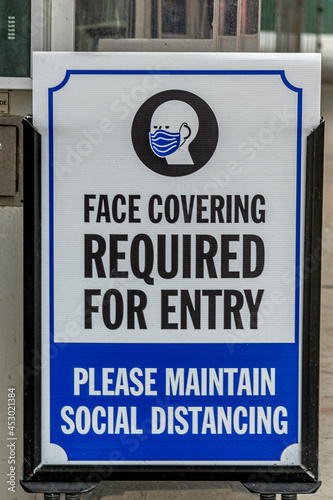 A sign informs commuters that a face covering is required to enter and passengers must maintain a social distance