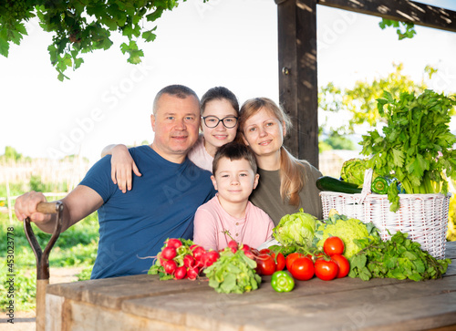 Parents with children relax at rustic table after harvesting ripe vegetables