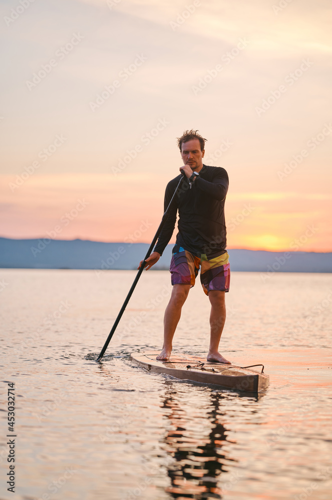 Paddling sup surf on quiet summer sunset