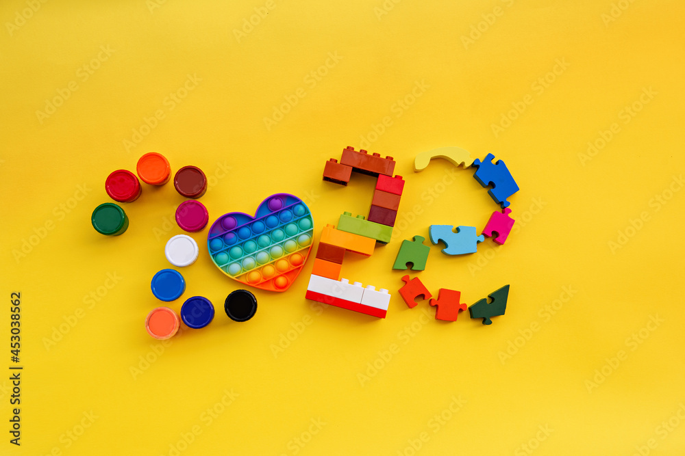 On an isolated yellow background numbers 2022, made up of children's toys. Copy space