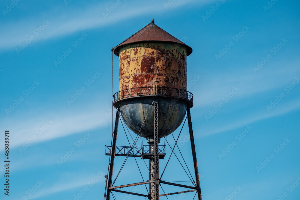 A rusty water tower against a blue sky