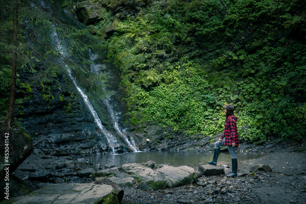 young hiking woman looking at waterfall