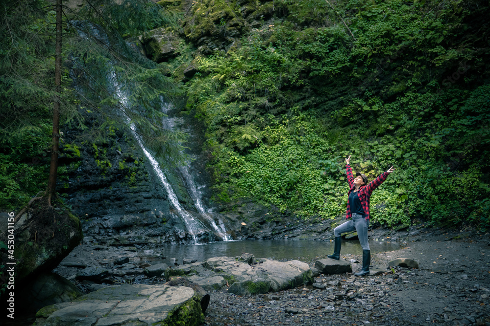 young hiking woman looking at waterfall